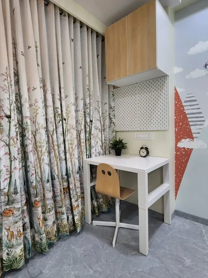 A cozy study nook with a simple white desk and a pegboard for organization. The nature-themed curtains add a whimsical touch.