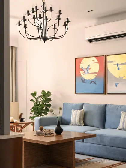 A detail of the living room, showing how the cool tones of the blue sofa are balanced by the warm hues in the artwork and the natural wood of the coffee table.