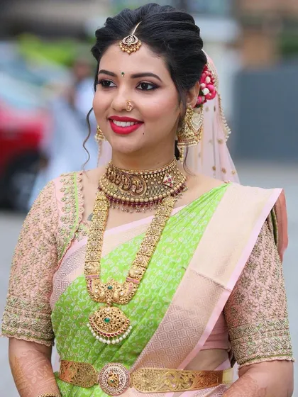 This bride is glowing in a parrot green and pink silk saree. I designed a custom sheer-sleeved blouse with intricate gold threadwork to create a light yet luxurious feel.