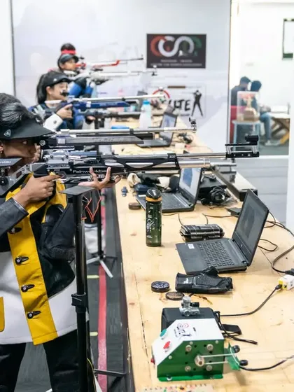 A shooter practices at her station, equipped with a laptop for shot analysis. This data-driven approach is central to our high-performance training methodology.