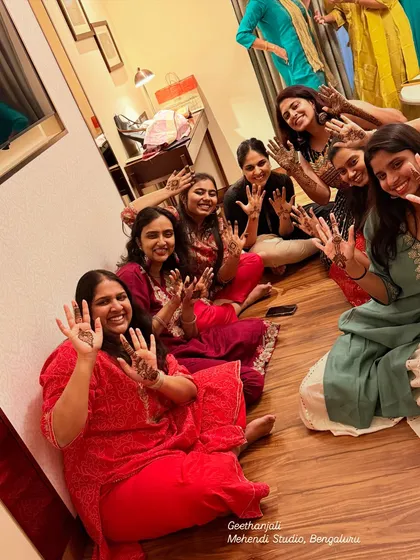 A happy group of friends and family showing their hands after a fun mehendi session at the Taj Bangalore.