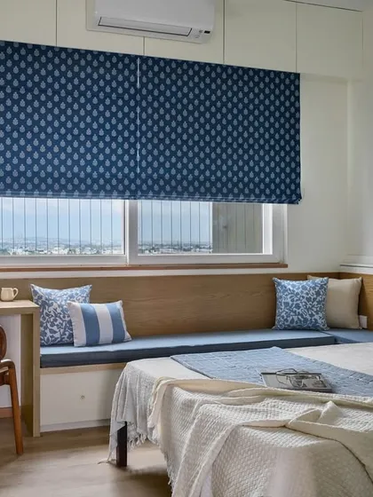 The guest room in our 'Malhar' project features a custom-built unit that transitions from a small study desk into a cozy bay window seat, complete with built-in storage underneath.