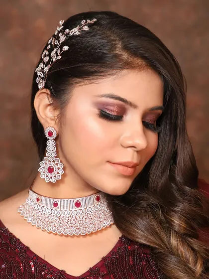 Make a statement at your next party with this gorgeous American Diamond choker set. The intricate design is studded with high-quality AD stones and beautiful ruby-colored accents, paired with matching drop earrings for a complete, polished look.