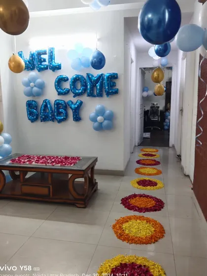 The "Welcome Baby" home setup, combining traditional flower rangoli with modern blue and gold balloon decorations.