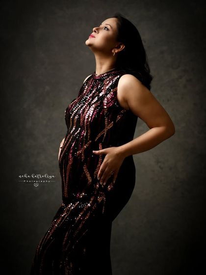 A profile view of another stunning sequined gown. The dramatic lighting highlights the texture of the dress and the beautiful pregnancy silhouette.