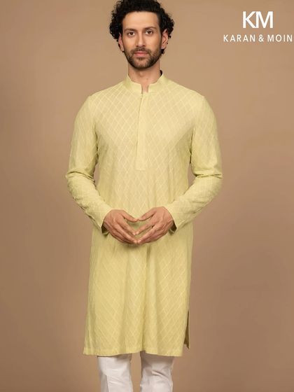 A full-length view of the pastel woven kurta, paired with simple white trousers. This showcases the effortless composition of the look, a study in poise, proportion, and the art of less.