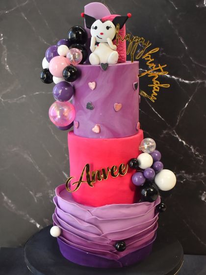 A whimsical three-tier Kuromi-themed cake for Anvee's birthday. The cake features shades of purple and pink, a fondant ruffle effect, and a cute Kuromi topper.
