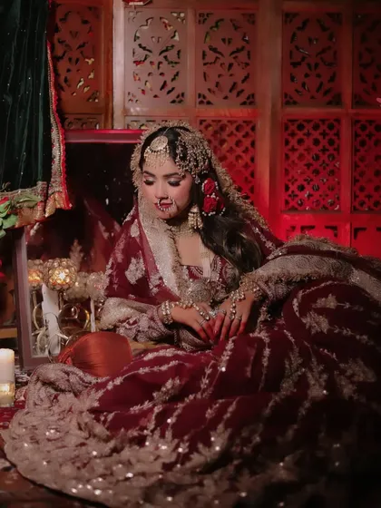 A wider, atmospheric shot of the Heeramandi-themed setup, with the model seated amidst candles and a treasure box.