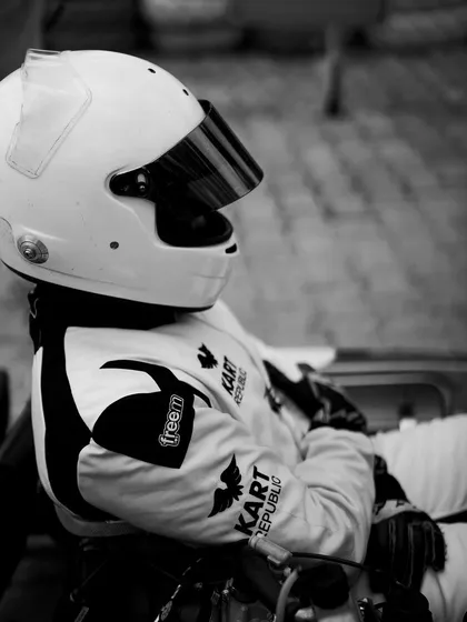 A black and white portrait of a driver in his Kart Republic race suit.