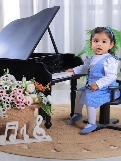 A beautiful, full-length portrait of the birthday girl at her miniature piano. The setup is elegant, with soft lighting and floral arrangements.