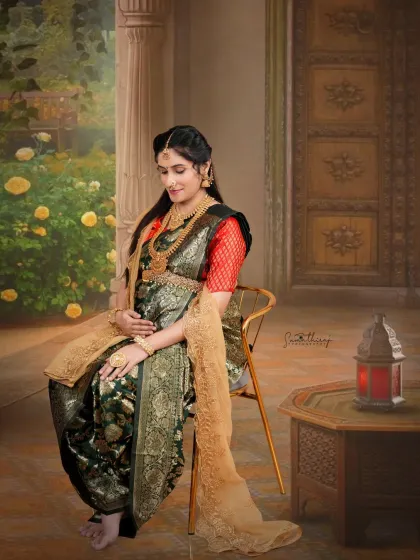 Seated gracefully in a traditionally draped saree, this mother-to-be embodies timeless elegance. The classic studio setup with an antique table and lantern adds to the regal and artistic feel of the portrait.