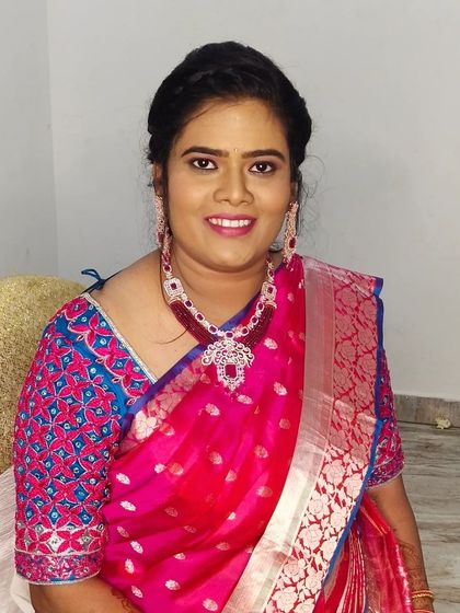 A smiling portrait of Sarita, looking happy and confident in her natural makeup and beautiful pink saree.