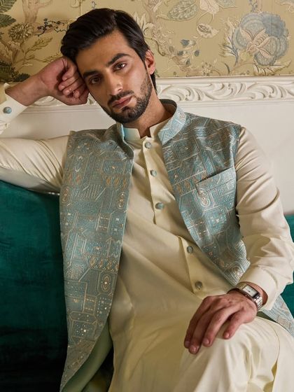 A close-up on the textured embroidery of the powder blue jacket. The mix of threads and sequins adds a subtle shimmer to the garment.