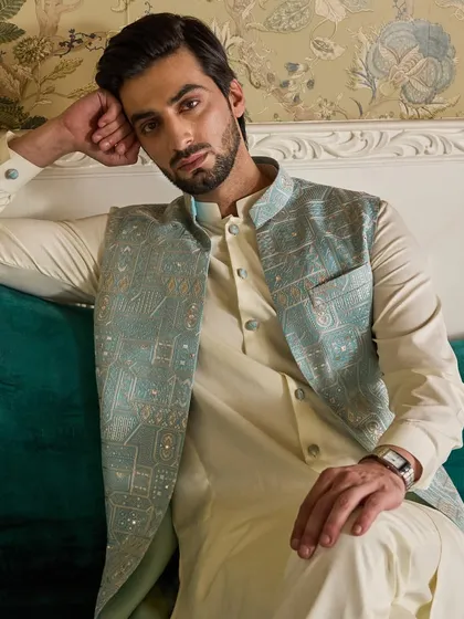 A close-up on the textured embroidery of the powder blue jacket. The mix of threads and sequins adds a subtle shimmer to the garment.