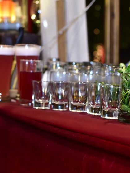 A lineup of empty shot glasses and fresh mint, ready for the next round of drinks at a festive event.