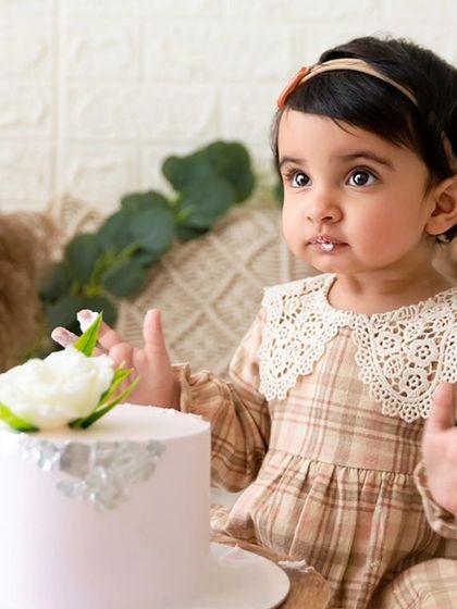 A close-up of the baby's reaction to her cake, set against a beautifully arranged boho-chic backdrop.