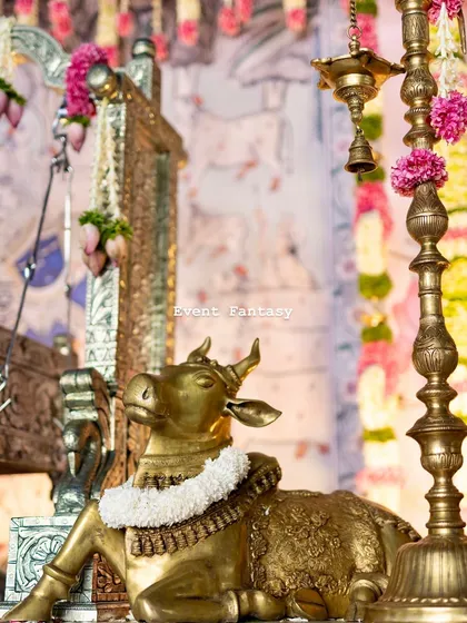 A detail shot of a brass cow statue adorned with a jasmine garland. These small, thoughtful touches are essential for creating an authentic and blessed atmosphere for a naming ceremony.