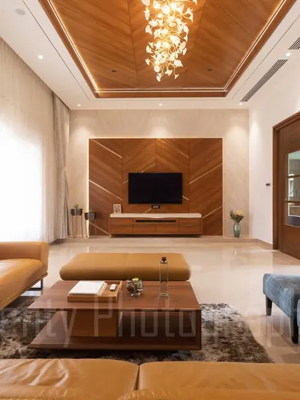 This expansive living area in one of our farmhouse projects showcases our approach to warm, luxurious interiors. We use a palette of rich textures, including natural wood ceilings and polished marble floors, to create a space that is both grand and inviting, with abundant natural light.