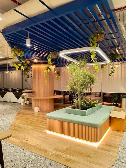 A wide view of the Bangalore project, showing how hanging plants and a large central planter with upholstered seating work together. This design creates a natural gathering spot within the office, promoting both relaxation and collaboration.
