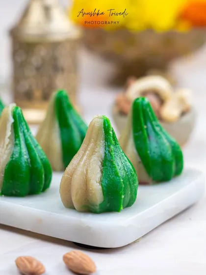 A close-up of the bi-coloured modaks, showing their perfect form. The shallow depth of field draws the eye right to the intricate details of the sweet.