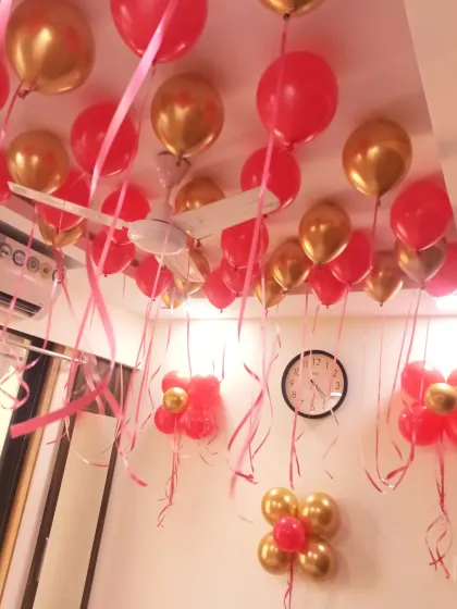 Red and gold balloons floating on the ceiling with ribbons hanging down, creating a festive and romantic atmosphere for a 'Just Married' celebration.