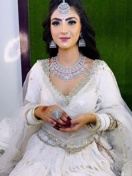 Another pose from the bride in the white lehenga, highlighting the sparkle of the AD necklace and maang tikka against the elegant outfit.