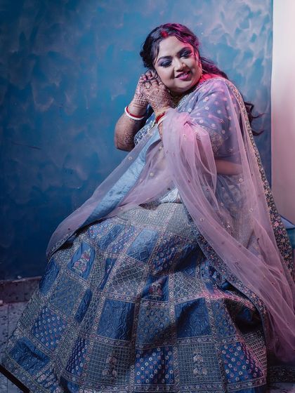 A full-length shot of this beautiful bridal reception look. The smokey eye makeup pairs perfectly with the intricate blue and silver lehenga for a cohesive and glamorous style.