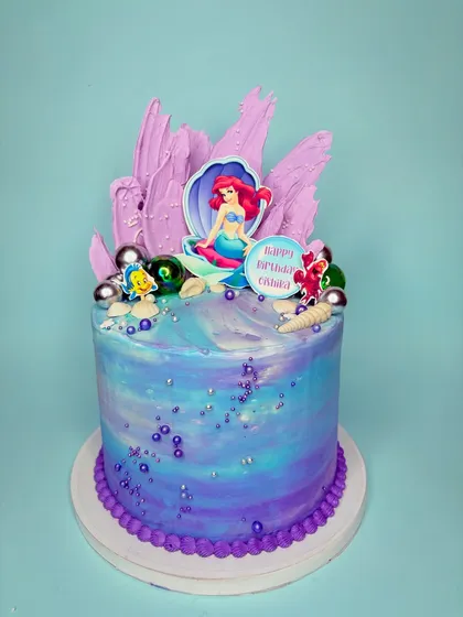 When I enjoy making a cake, it really shows. This Little Mermaid cake was so much fun to bring to life, with its purple and blue watercolor buttercream, chocolate shell details, and Ariel herself taking center stage.