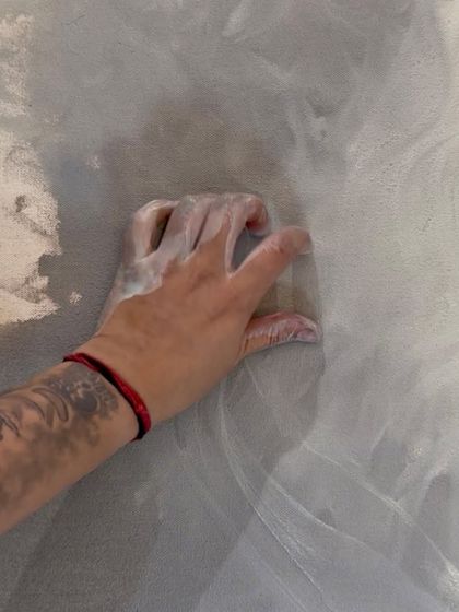 A close-up of my hand blending white paint into a textured grey canvas. This is a moment of quiet connection between me and my work.
