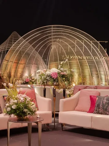 A cozy lounge nook at the musical reception, with plush pink sofas set against the backdrop of the grand, illuminated arched structures.