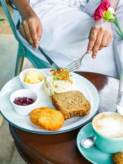 A lifestyle shot of someone enjoying a healthy breakfast of egg-white scramble and hash browns with a coffee. This image feels personal and captures a relatable morning routine.