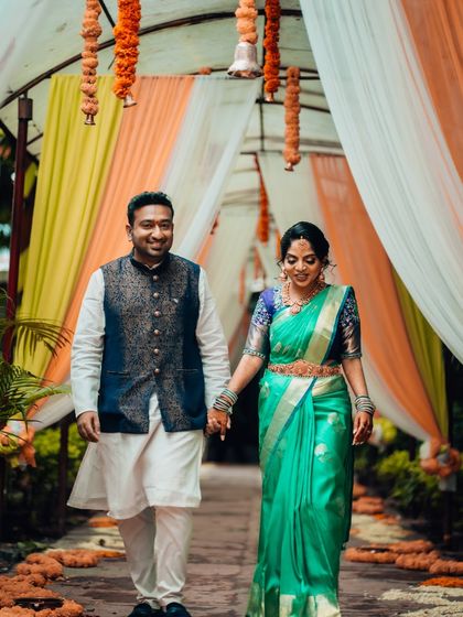 A happy couple walks hand-in-hand down a path decorated with drapes and flowers, capturing their joy after the ceremony.