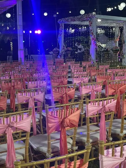 Rows of elegantly decorated chairs ready for guests at a wedding reception. The pink sashes add a pop of color and tie the seating in with the overall theme.