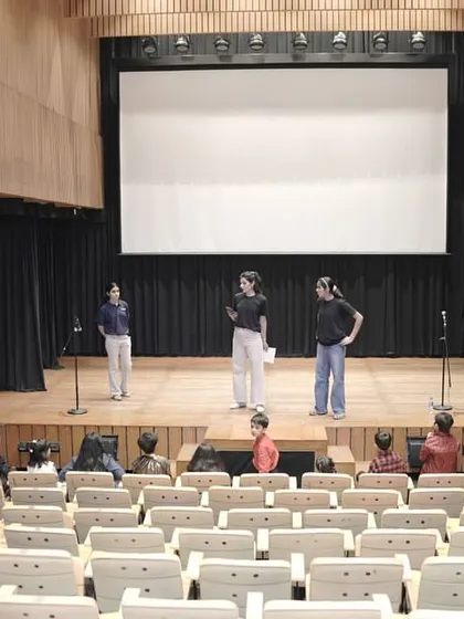 A wide shot of a rehearsal in an empty auditorium. This shows the scale of the space the children learn to command with their presence.