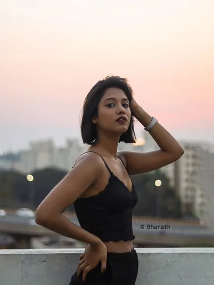 Capturing the urban vibe of Bangalore at sunset. This rooftop portrait uses the soft, warm glow of the golden hour to create a moody and atmospheric shot, highlighting the model's silhouette against the city skyline.