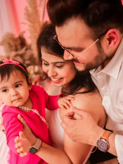 A close-up of a happy family. The pink background and their joyful interactions create a warm and loving portrait.