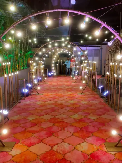A modern entrance walkway with arched metal frames and exposed bulb lighting, set over a patterned carpet for a stylish and contemporary look.