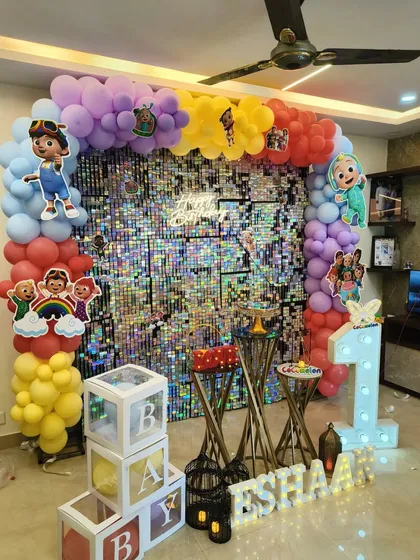 For a truly vibrant celebration, I combine popular character themes with eye-catching backdrops. This Cocomelon first birthday party features a full silver shimmer wall, a rainbow balloon arch with character cutouts, a large marquee '1', and 'BABY' blocks, ensuring a festive and fun look.