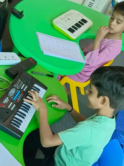 Two young students practicing side-by-side on their keyboards. Our classes are designed to be interactive and engaging for kids.