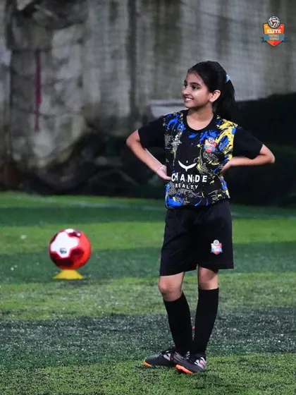 A young girl stands confidently on the pitch, ready for the next drill. We empower all our players to be leaders.