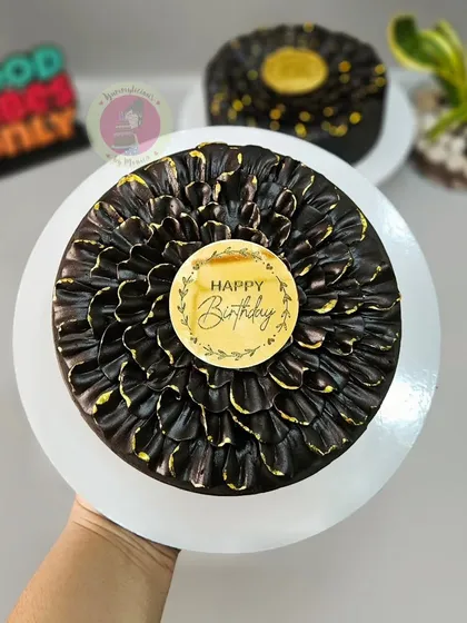 Holding up the finished chocolate petal cake, showing the beautiful texture and gold-dusted edges.