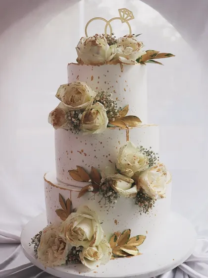 A closer look at the details on this three-tier white and gold wedding cake. The gold-dusted roses and delicate baby's breath create a look of pure sophistication.