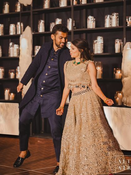 The happy couple dancing in front of a modern candle installation at their 'Muted Melodies' sangeet. The design was all about creating a warm, cozy, and understated luxury vibe.