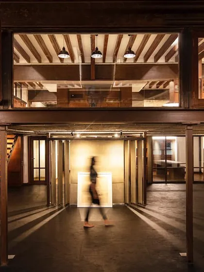 An atmospheric shot of the 'Tianu Revival Project.' The design plays with light and shadow, using a double-height space and a mezzanine level to create a dramatic and layered retail experience that feels both historic and contemporary.