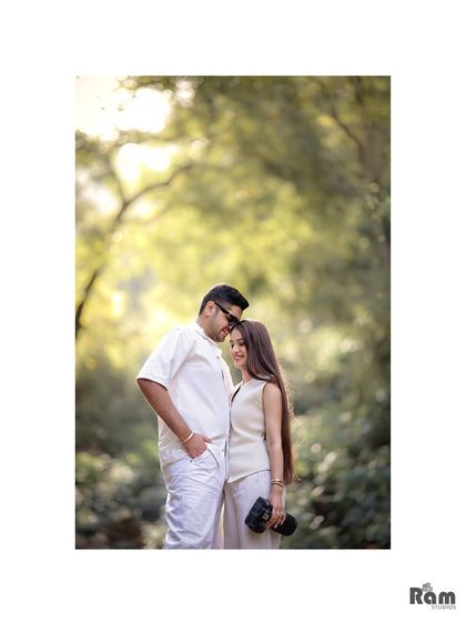 A classic, romantic portrait taken in a beautiful, shaded grove. The vertical framing and soft background create a timeless and intimate feel for this pre-wedding photograph.