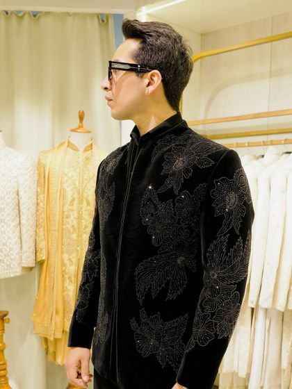 A side profile of the black velvet bandhgala with intricate floral beadwork. The structured fit and detailed craftsmanship create a powerful and elegant silhouette.