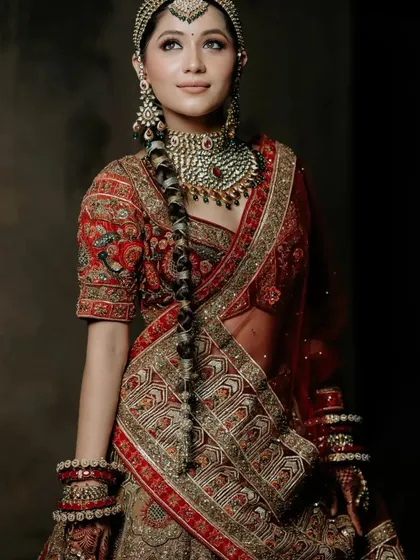 A three-quarter view of the model, highlighting her long, decorated braid and the stunning embroidery of her outfit.