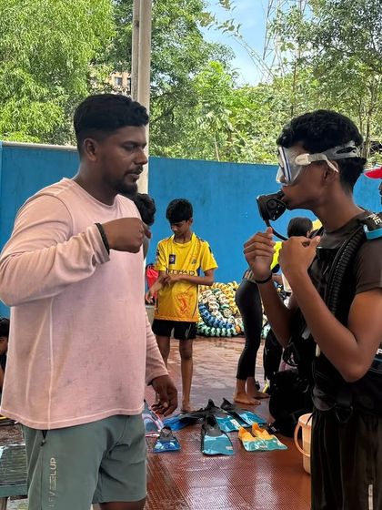 An instructor provides one-on-one guidance on how to use the scuba regulator before a participant enters the pool.