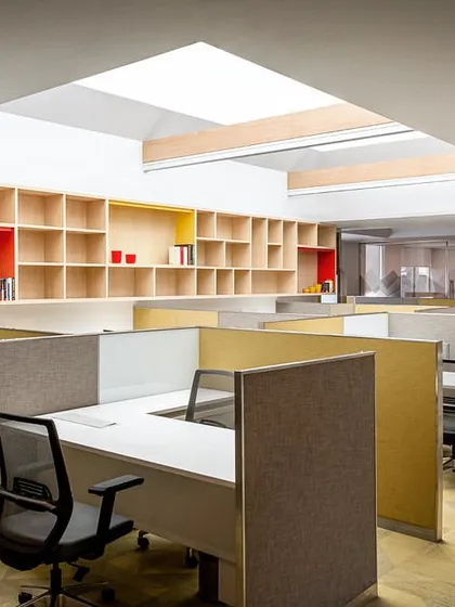 The open-plan design studio on the director's floor features clean, modern workstations and extensive shelving, with a large skylight providing ample natural light.