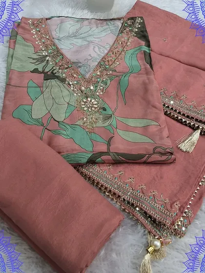 A lovely peach-colored dress material with a digital floral print top. The dupatta is simple yet elegant with a delicate border and tassels, perfect for a sophisticated look.